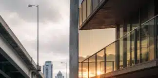 Class War: Split image showing a luxury high-rise balcony on one side and a tent encampment under a highway overpass on the other, Canadian city skyline visible in both halves.