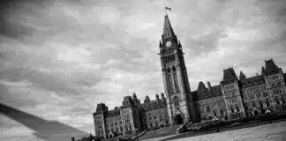Canada's Democracy: Black and white photo of the Canadian Parliament buildings, slightly tilted, with a long shadow falling across the foreground.